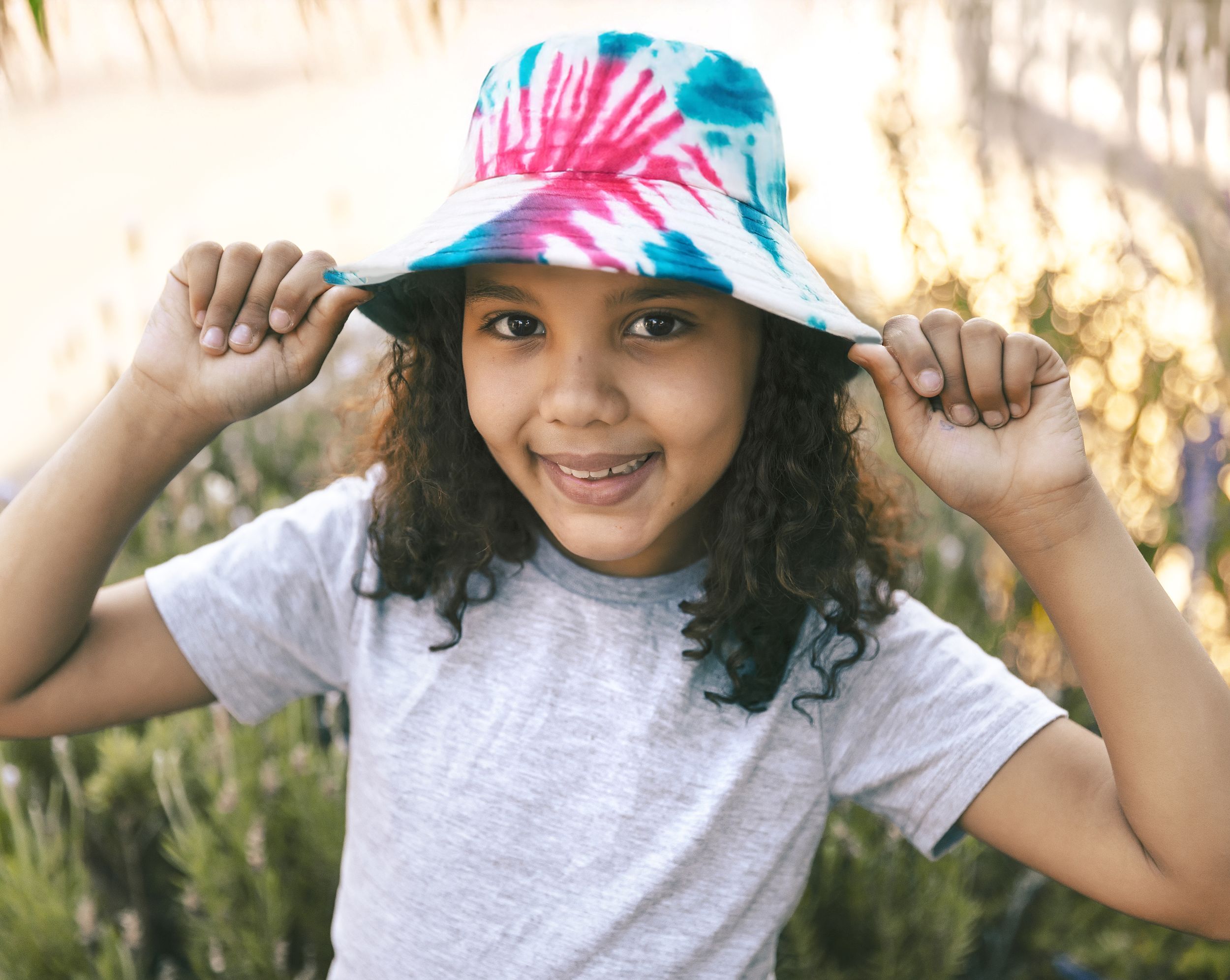 Smiling child wearing tie dyed bucket hat